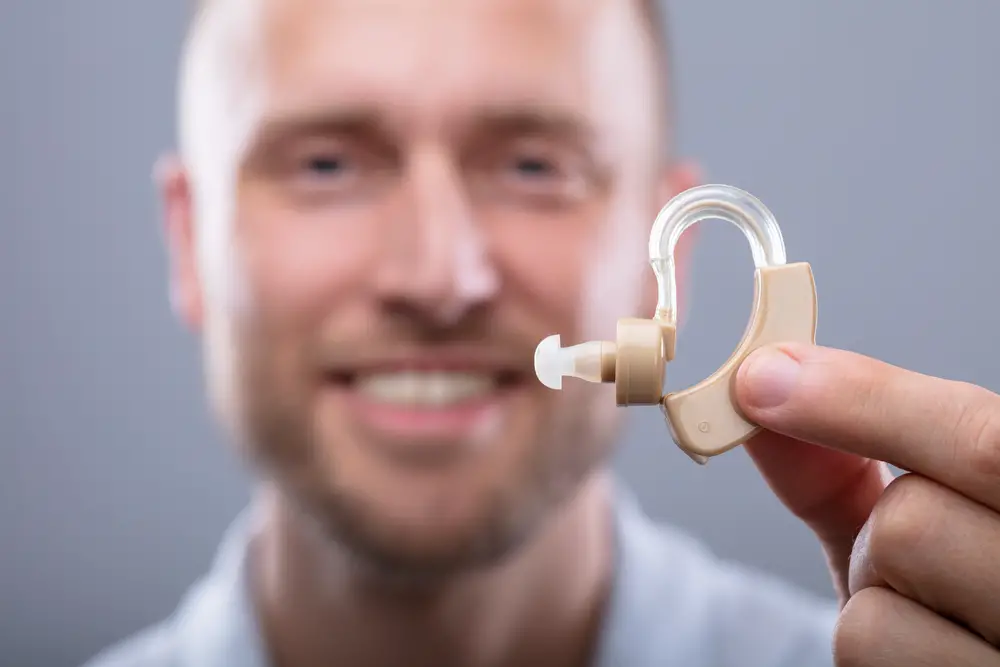 Close-up Of A Happy Man Holding Hearing Aid